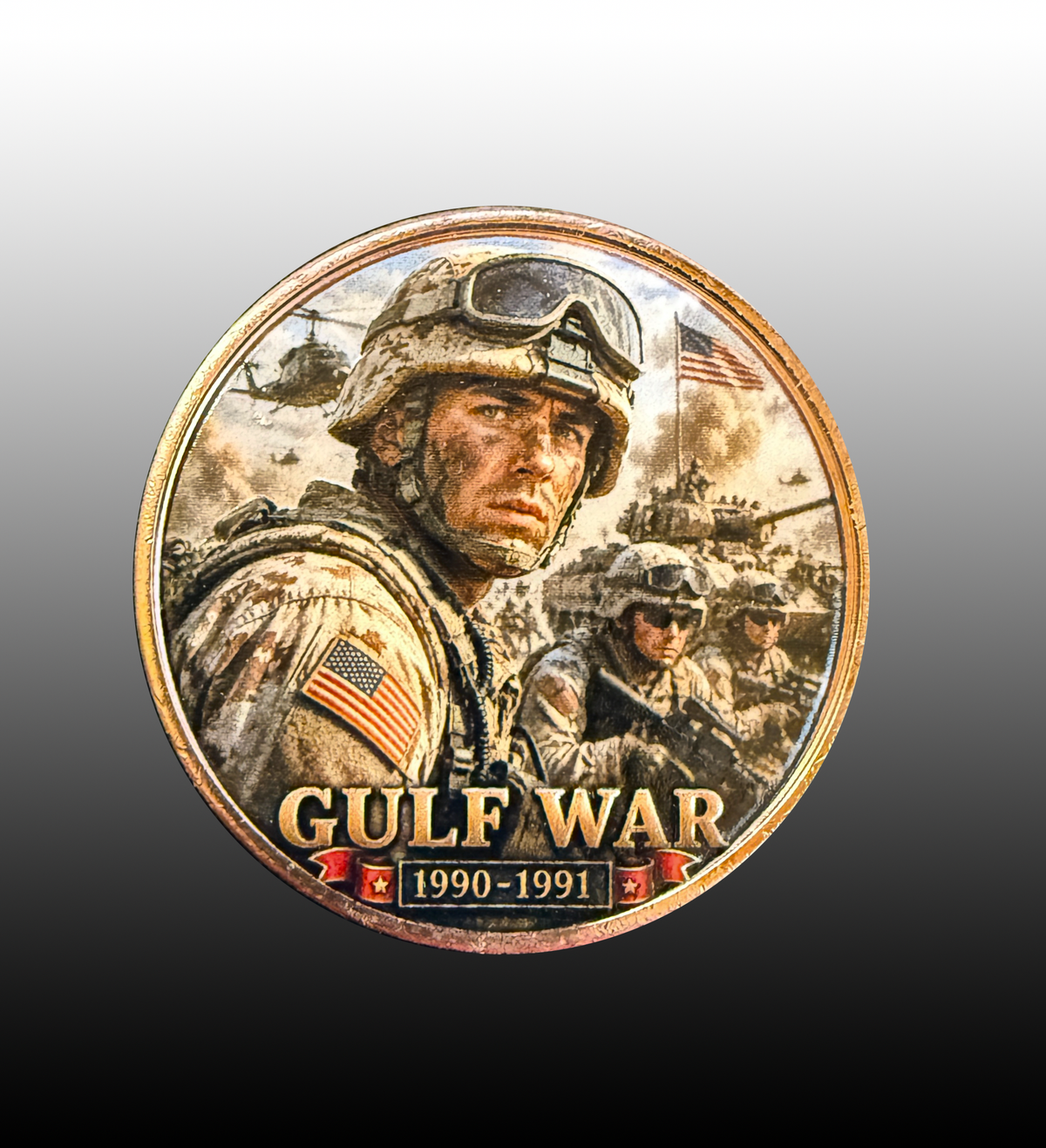 A circular commemorative coin or medallion featuring a military portrait with the text 'GULF WAR 1990-1991' and small American flags, shown on a dark gray to black gradient background.